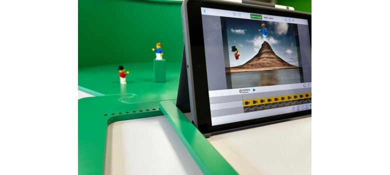 Eine grüne Kunststofffläche ist zu sehen auf der 2 Playmobilfiguren stehen. Davor steht ein Laptop, auf dem die Szene der beiden Figuren abgebildet wird.