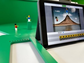 Eine grüne Kunststofffläche ist zu sehen auf der 2 Playmobilfiguren stehen. Davor steht ein Laptop, auf dem die Szene der beiden Figuren abgebildet wird.