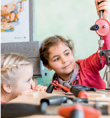 Zwei Mädchen betrachten sich ein technisches Gerät.